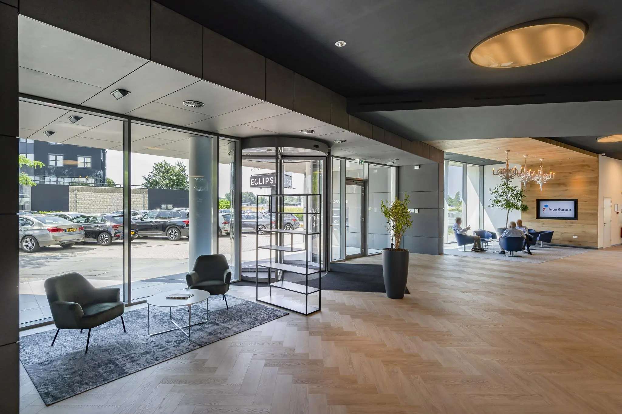 Moderne entreehal van Rivium Quadrant met zithoeken, draaideur en uitzicht op de parkeerplaats.